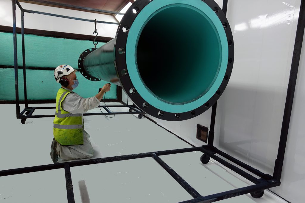 Coatings inspection on a lined pipe section in the Northpoint wet paint booth